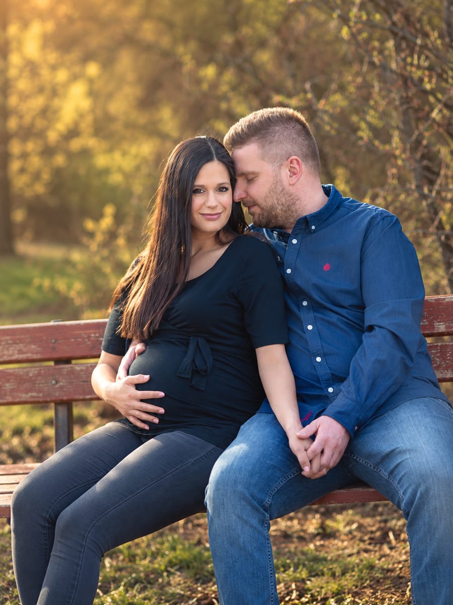 Kriszti and Szabolcs on a park bench in the evening sun, expecting their first son